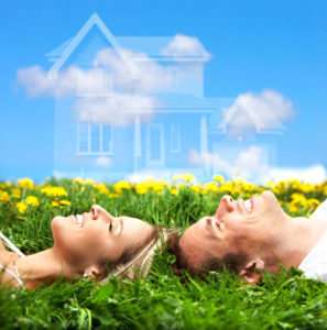 young couple lying on a grassy field as a dream home appears above their heads