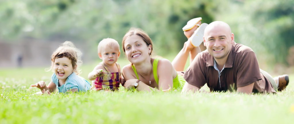 happy young family lying on the grass outside their new homes