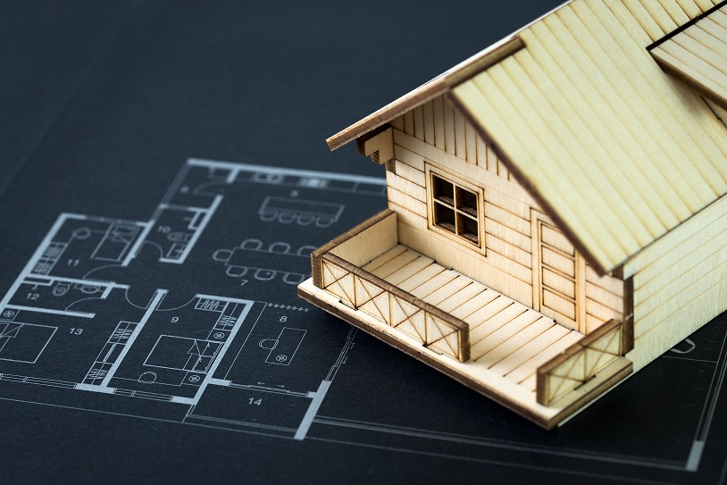 Miniature house rest on top of home blueprint